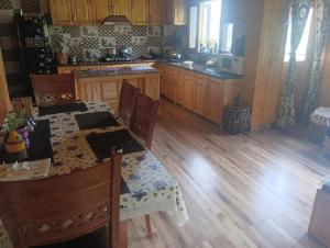 a kitchen with a table and a kitchen with wooden floors at Anuppam Home Stay in Kulu