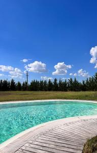 une piscine d'eau bleue à côté d'un pont en bois dans l'établissement Cottage indipendente con piscina privata, à Masi San Giacomo