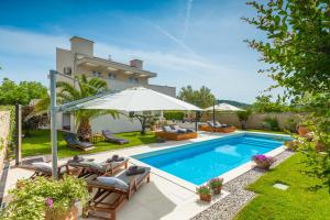 een zwembad met stoelen en een parasol naast een huis bij Villa Bella- White in Rovinjsko Selo
