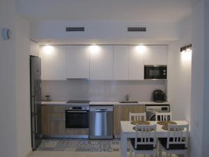 a kitchen with white cabinets and a table and chairs at Family Apartment in Vilanova i la Geltrú