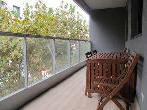 un balcón con una mesa de madera y sillas. en Family Apartment, en Vilanova i la Geltrú