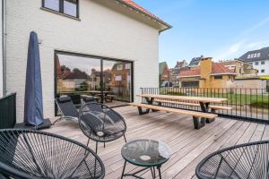 una terraza con mesa de picnic, sillas y banco en Sublieme, ruime luxe villa 10p met terras én tuin en Koksijde