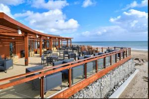 - un restaurant sur la plage avec l'océan en arrière-plan dans l'établissement The Warren Holiday Park - Family Chalet, à Abersoch