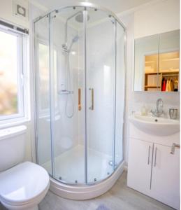 a bathroom with a shower and a toilet and a sink at The Warren Holiday Park - Family Chalet in Abersoch