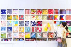 a woman standing in front of a wall filled with wrapping paper at OMO5 Kyoto Sanjo by Hoshino Resorts in Kyoto