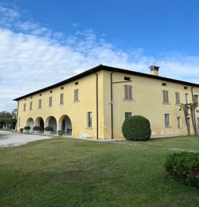un grande edificio giallo con un prato davanti di Corte San Lorenzo a Desenzano del Garda