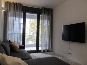 a living room with a couch and a flat screen tv at Family Apartment in Vilanova i la Geltrú