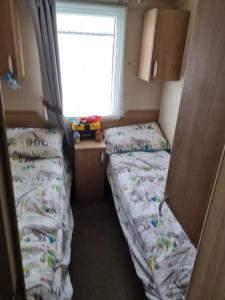 um pequeno quarto com 2 camas e uma janela em Beautiful 3 bed holiday home em Port Seton