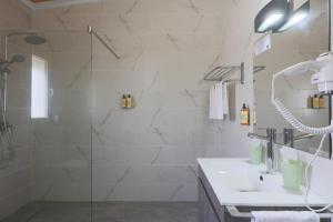 La salle de bains blanche est pourvue d'une douche et d'un lavabo. dans l'établissement Parrots`Village, à Rabo de Peixe