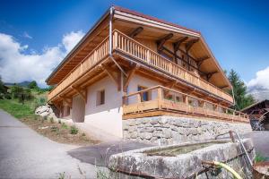 a house with a wooden balcony on the side of it at La Ferme des Fingères in Cordon