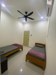 Cette chambre dispose de 2 lits et d'un ventilateur de plafond. dans l'établissement Sejati Homestay bukit payong marang k.terengganu, à Kuala Terengganu