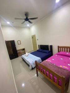 - une chambre avec 2 lits et un ventilateur de plafond dans l'établissement Sejati Homestay bukit payong marang k.terengganu, à Kuala Terengganu