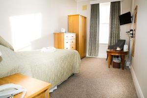 a hotel room with a bed and a desk and a window at The Cumberland Hotel in Eastbourne