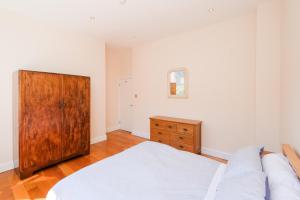1 dormitorio con 1 cama y armario de madera en Lovely 2 bed flat in canal side gated development, en Londres