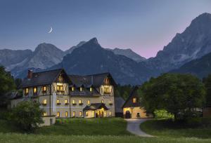 a large white house with mountains in the background at Appartementhaus Madlen in Hinterstoder