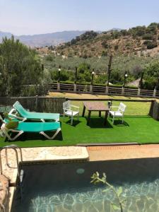 a patio with chairs and a table next to a pool at Apartamento El Mirador Rocabella in El Chorro