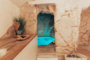 a bathroom in a cave with a blue tub at Grotta Carlotta in Ostuni