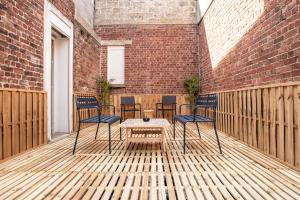 a patio with chairs and a table on a wooden deck at Le Cottage du Louvre in Lens