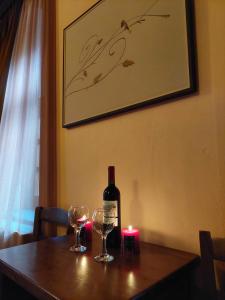 a bottle of wine and two glasses on a table with a candle at Archontiko Geki 1876 in Papingo +32 photos
