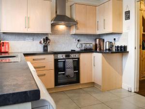 a kitchen with wooden cabinets and a stove top oven at Quarry Cottage in Bethesda