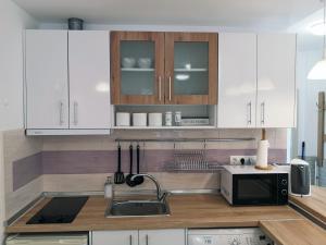a kitchen with white cabinets and a sink and a microwave at Comfortable Ground Floor Studio in Primorsko +8 photos