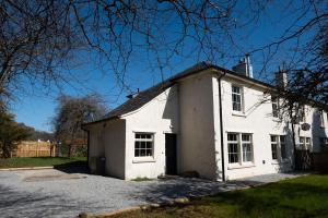 una antigua casa blanca con entrada en Parkside, The Loch Ness Cottage Collection en Inverness