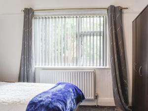 sypialnia z oknem z zasłonami i łóżkiem w obiekcie Huddersfield House, Wood View w mieście Huddersfield