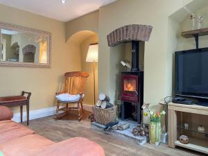 a living room with a fireplace and a tv at Yew Tree Cottage in Old Brampton
