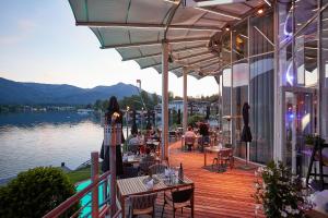 eine Terrasse mit Tischen und Stühlen in einem Gebäude neben dem Wasser in der Unterkunft Scalaria Sunset Wing in St. Wolfgang