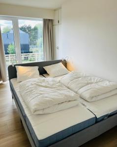 a large bed in a room with a large window at duinpark62: gezellig 3 slaapkamer-appartement inclusief garage in Oostduinkerke