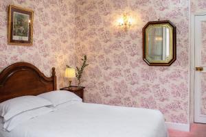 a bedroom with a white bed and pink wallpaper at Hotel des Grandes Ecoles in Paris