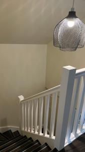 Un escalier blanc avec une lampe suspendue et un plafond dans l'établissement City Centre Bridge Street Apartment, à Kirkwall