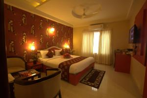 a hotel room with a bed and a chair at Royal shades kodihali in Bangalore