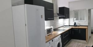 a kitchen with black cabinets and a white refrigerator at Alexa suite in Las Palmas de Gran Canaria