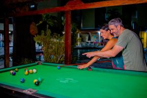 Rio das Pedras Thermas Hotel في كالدس نوفاس: رجل وامرأة يلعبان البلياردو على طاولة بلياردو