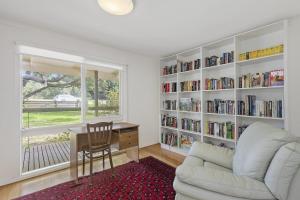 a living room with a couch and a desk and book shelves at Beach Side in Aireys Inlet