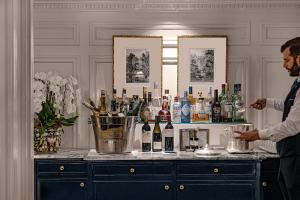 a man standing at a bar with bottles of alcohol at Relais Christine in Paris
