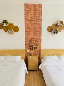 a bedroom with two beds and a brick wall at Mi Casa Homestay in Da Lat