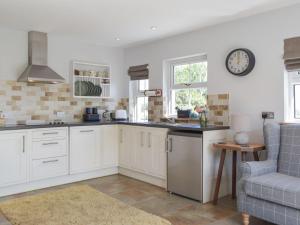 a kitchen with white cabinets and a clock on the wall at Hafan Fach Cottage in Pembroke