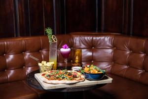 a table with a pizza and chips on a leather couch at Avoca Hotel in Newcastle