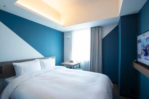 a blue bedroom with a white bed and a television at Prince Smart Inn Hakata in Fukuoka