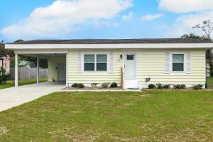 a yellow house with a lawn in front of it at Ginny's Coastal Cottage in Oak Island