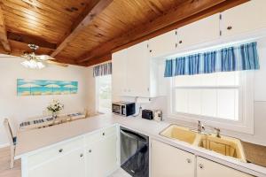 a kitchen with white cabinets and a sink and a window at Ginny's Coastal Cottage in Oak Island