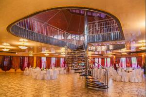 un gran salón de banquetes con mesas blancas y una escalera de caracol en Vyshegrad Castle Hotel, en Vyshgorod