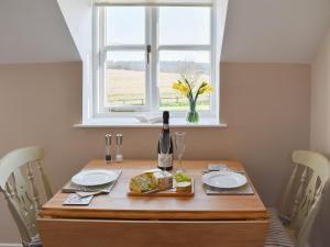The Stables في Bealings: طاولة غرفة طعام مع زجاجة من النبيذ ونافذة