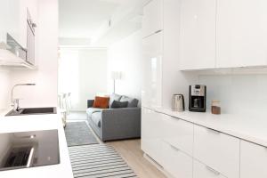 una cucina e un soggiorno con armadi bianchi e divano di ULEABO Neat 48 m2 two-room flat with sauna a Oulu