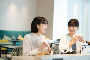 two women sitting at a table eating food at Prince Smart Inn Hakata in Fukuoka