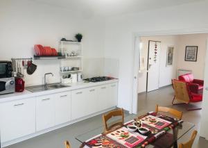 eine Küche mit weißen Schränken und einem Tisch im Zimmer in der Unterkunft ROGOS Casa Vacanze in Ragusa