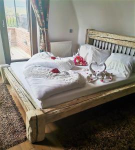 een houten bed met witte lakens en decoraties erop bij Vintage Home Vendégház in Miskolctapolca