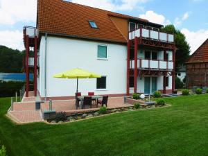 ein Haus mit einer Terrasse mit einem Tisch und einem Sonnenschirm in der Unterkunft Ferienwohnungen MAXIMA in Bad Arolsen